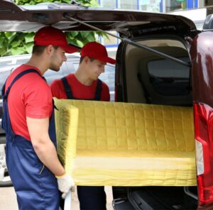 Günstig umziehen in Sinsheim: Umzugshelfer laden ein gelbes Sofa in einen Transporter