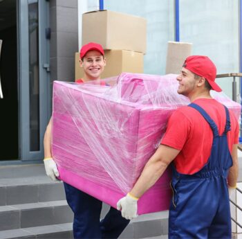 Zwei Umzugshelfer tragen ein in Folie gepacktes Möbelstück – Umzug in Sinsheim